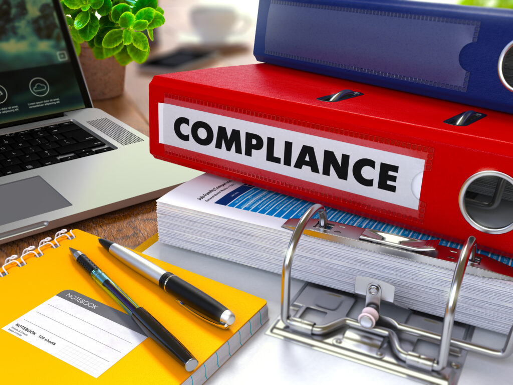 Desk with regulatory binders, compliance paperwork, and laptop for home health ops planning