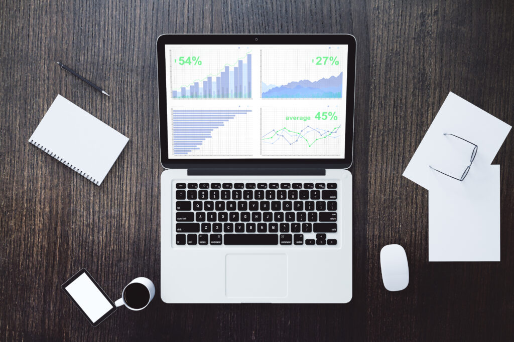 Laptop showing business graph charts on a wooden office desk