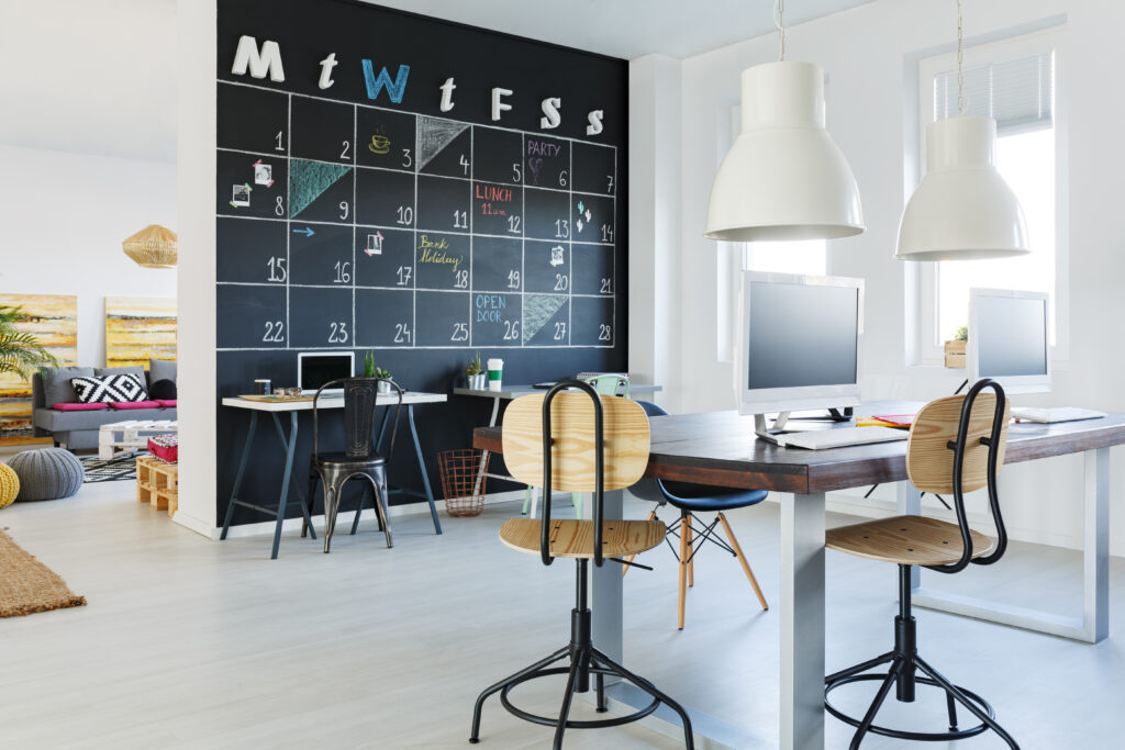 Open workspace with blackboard wall, desk, chairs, and computers for schedule planning