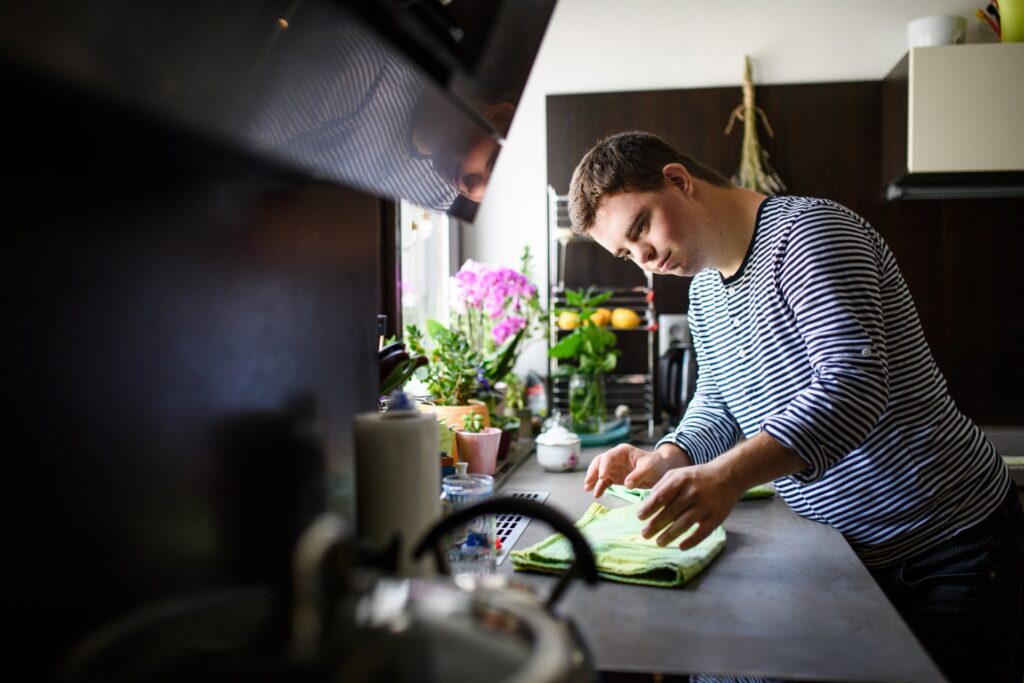 Adult man with Down syndrome folding a towel in his home kitchen