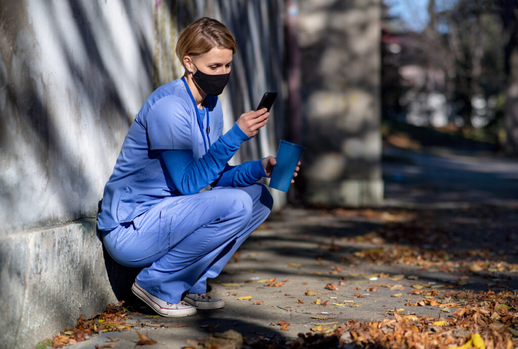 Home care caregiver checking smartphone schedule outdoors before a visit