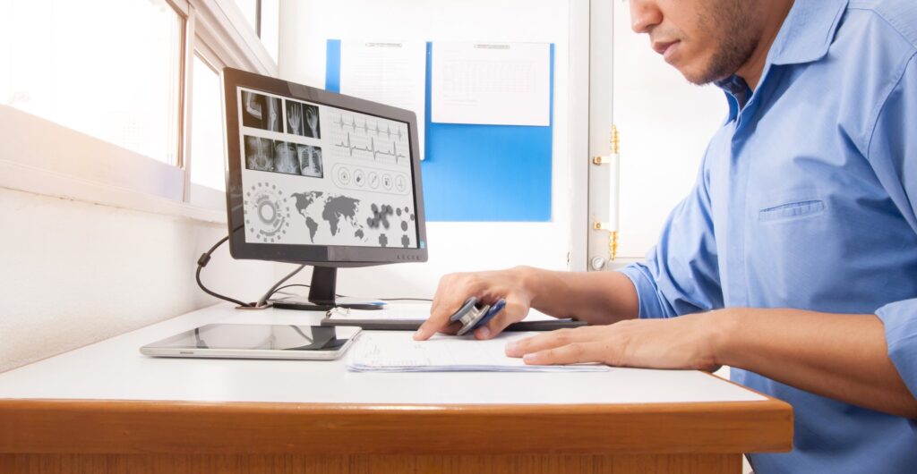 Medical reviewer working through claim paperwork at a desk with a computer