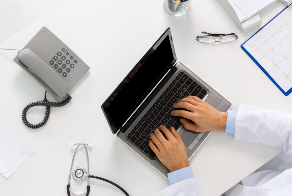 Doctor hands typing on a laptop computer at a medical office desk