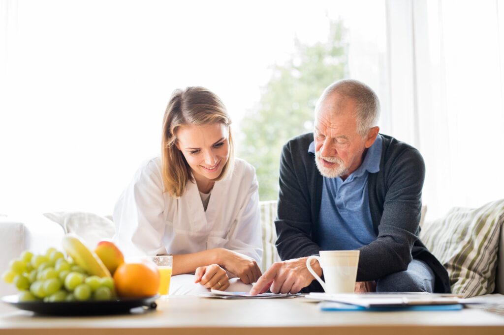 Home health visitor reviewing information on a tablet with a senior man during a home visit
