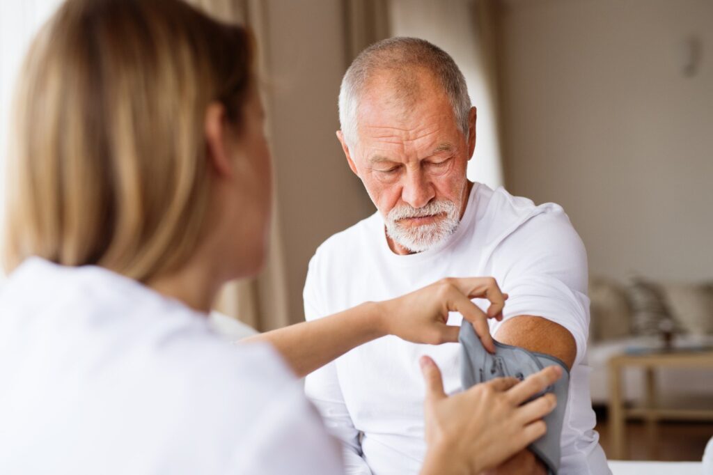 Home health visitor checking the blood pressure of a senior man during a home visit